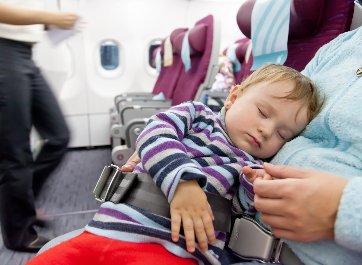 Ein Kind sitzt im Schoß der Mutter in einem Flugzeug
