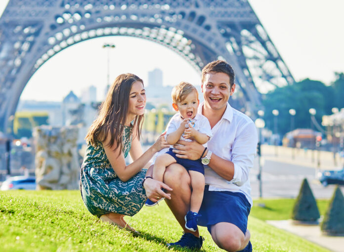 Eine glückliche dreiköpfige Familie genießt ihren Urlaub in der Nähe des Eiffelturms in Paris, Frankreich