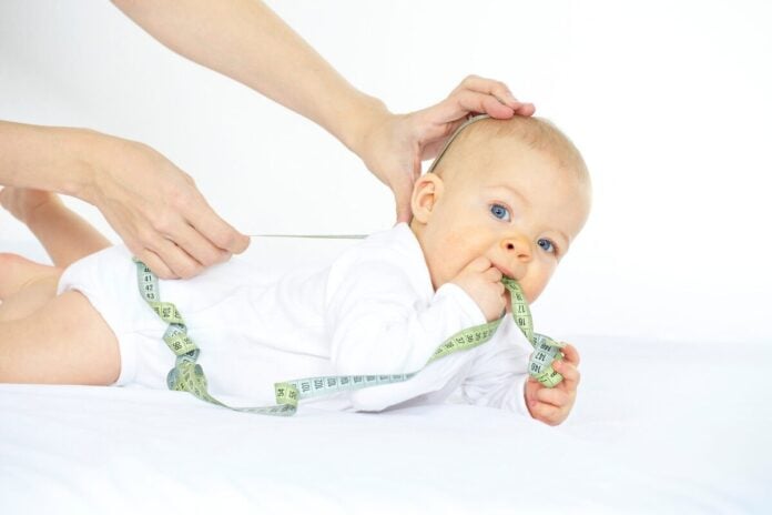 Baby beim Vermessen mit Maßband - hilfreiche Orientierung für die Baby Größe Gewicht Tabelle zur Entwicklungskontrolle